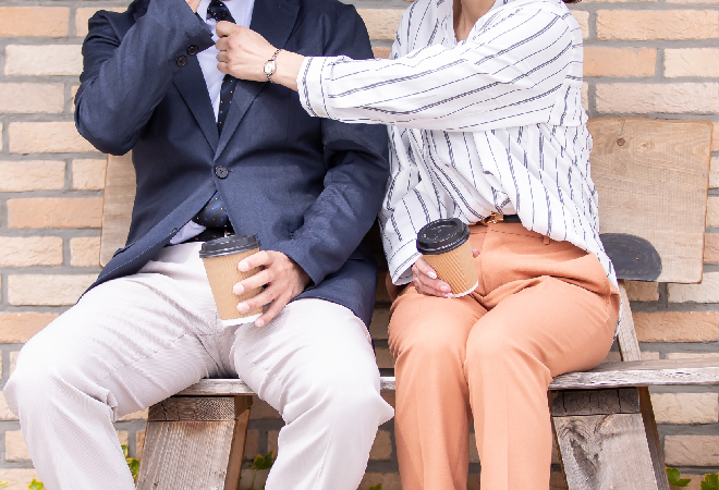 男性のネクタイを整える女性の姿。