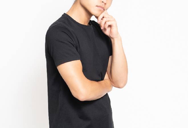 腕を組んで疑う様子の男性の写真。