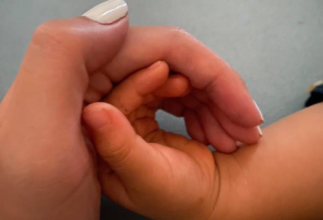 赤ちゃんの手を包む女性の手。