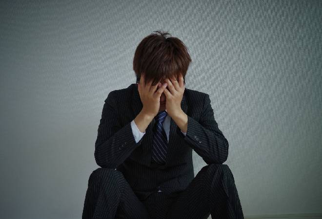 項垂れるスーツの男性。